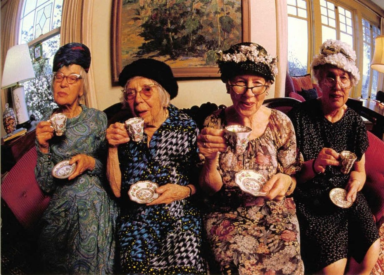Four older women enjoying tea together in a warmly decorated room.