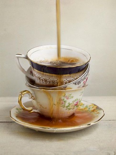 Tea pouring into stacked vintage floral teacups on a saucer.